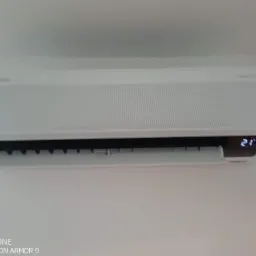 Biała jednostka klimatyzacji Samsung WindFree zamontowana na ścianie, wyświetlająca temperaturę 21 stopni Celsjusza.