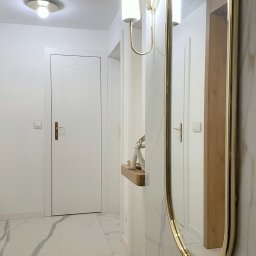 Pracownia Projektowa UNIQUE Anna Klimczewska-Waszczyk - Nowoczesny przedpokój z marmurową podłogą, białymi drzwiami i złotym lustrem. Minimalistyczna konsola z dekoracją. Oświetlenie ścienne w stylu glamour.