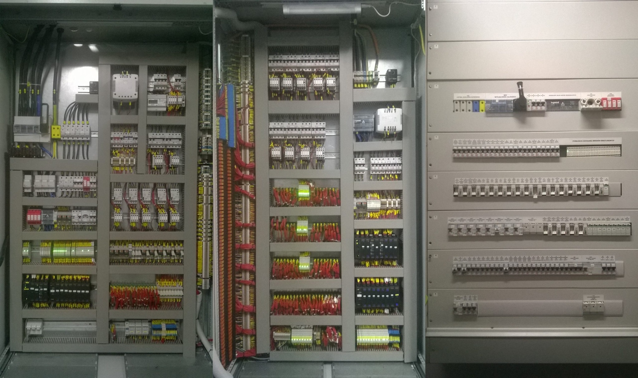 Rozbudowana, otwarta szafa sterownicza z licznymi przewodami, bezpiecznikami i elementami elektrycznymi ułożonymi w regularny sposób.