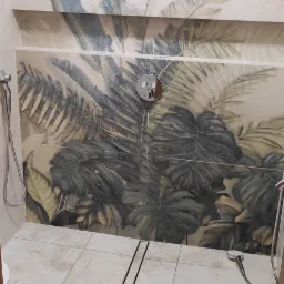 Kabina prysznicowa z odpływem liniowym i płytkami z motywem liści tropikalnych na ścianach.