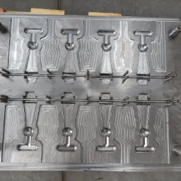 Metalowa forma z wyfrezowanymi gniazdami, prawdopodobnie do odlewania plastikowych elementów w kształcie butelek, z widocznymi śladami obróbki skrawaniem i elementami mocującymi.