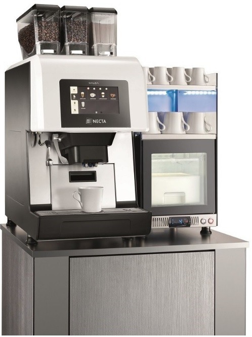 Profesjonalny automat do kawy z trzema pojemnikami na ziarna i proszek, z wbudowaną chłodziarką na mleko i podświetlanym regałem na filiżanki, stojący na szafce z szarą okleiną.