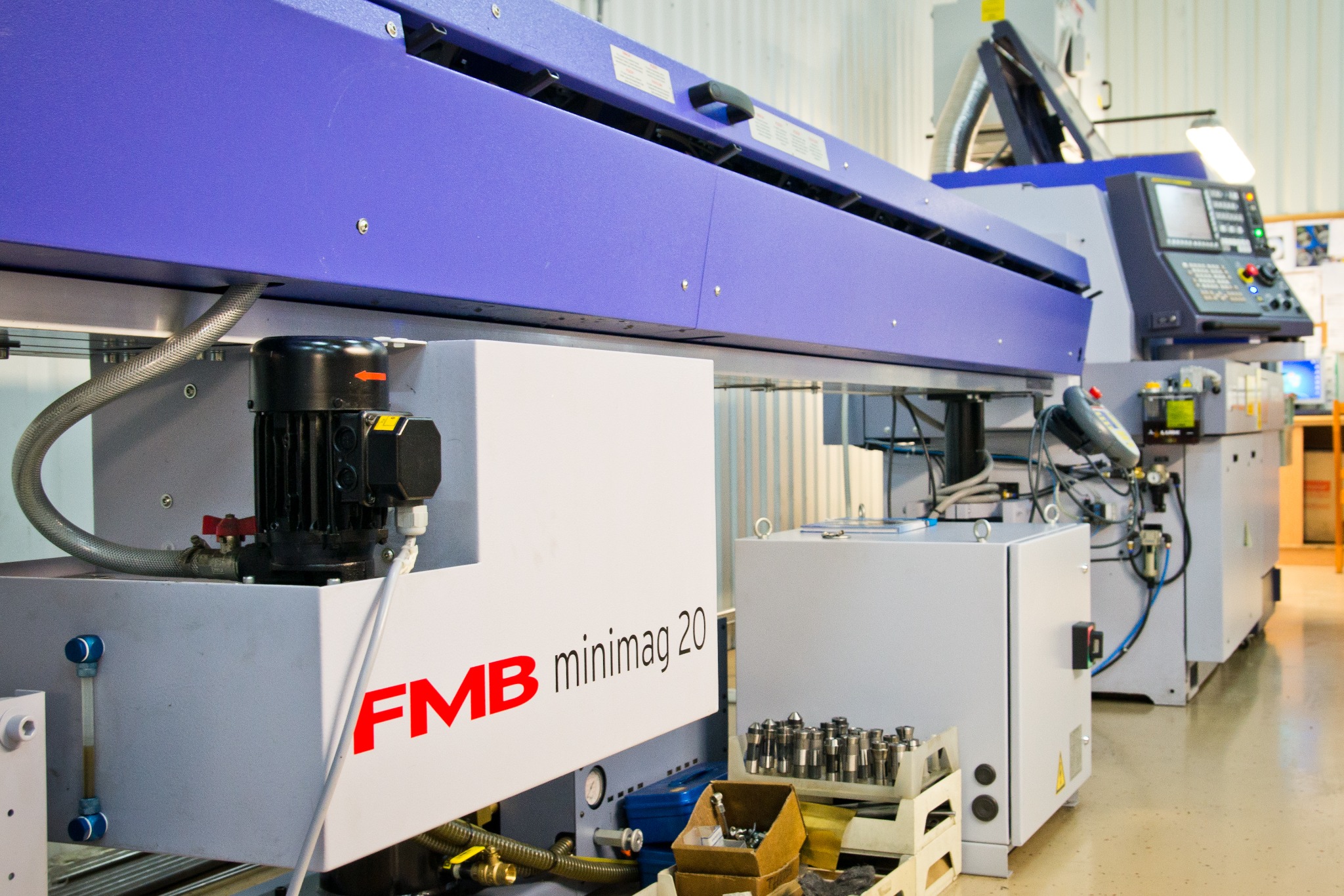 Widok z bliska na maszynę CNC FMB minimag 20 w warsztacie, widoczne narzędzia i elementy sterujące.