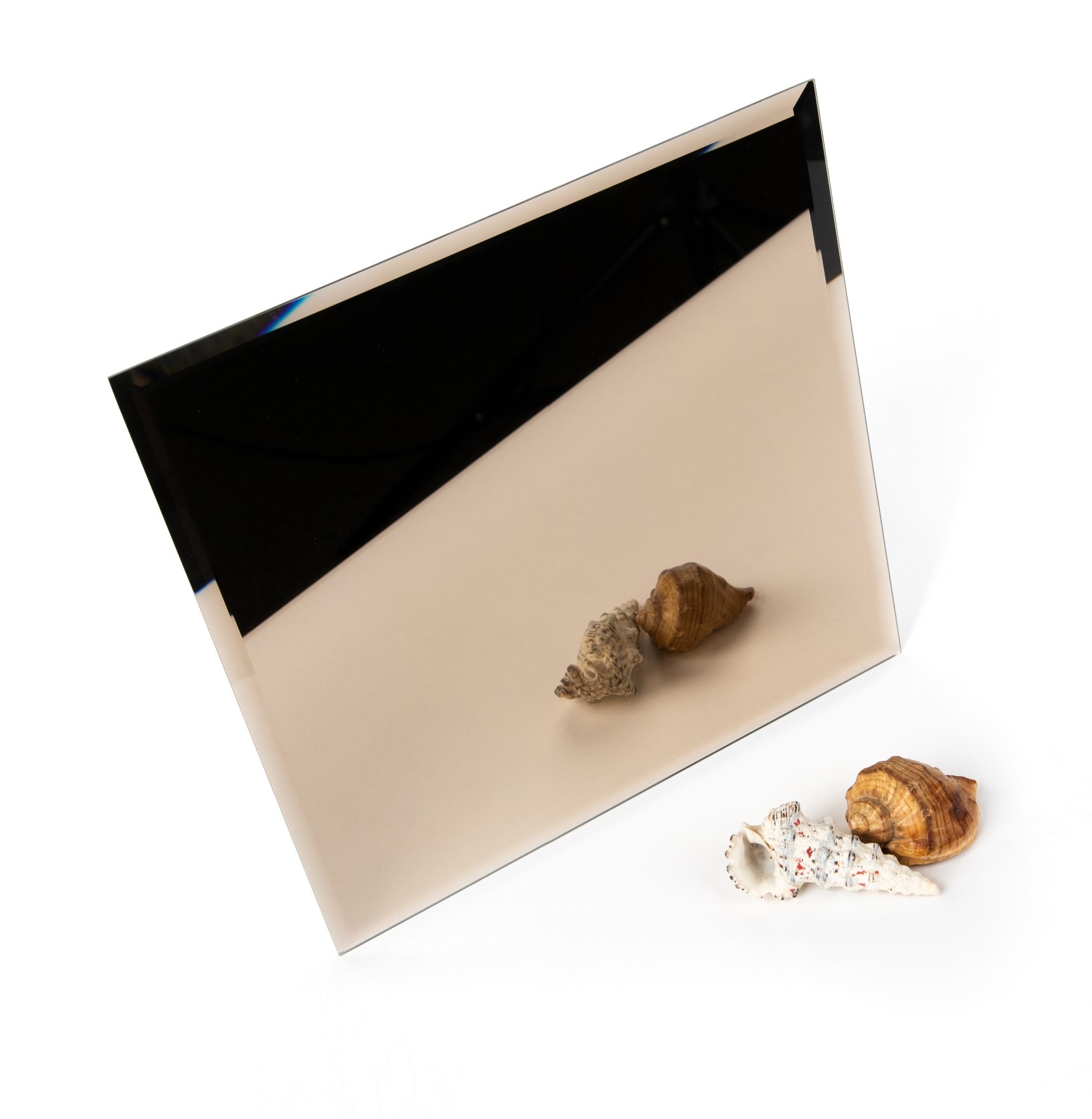 Beżowe lustro w kształcie kwadratu, ustawione pod kątem na białym tle, z dwoma zestawami muszelek na powierzchni i obok.
