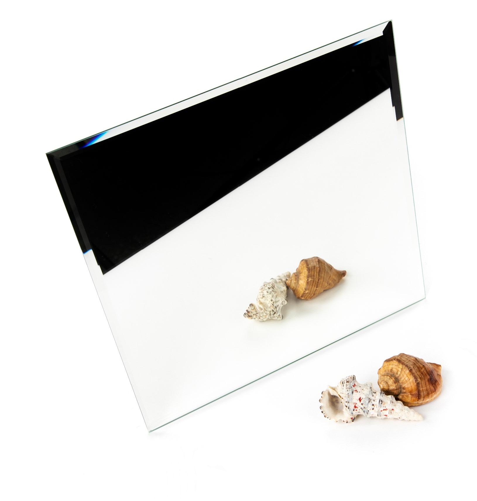 Szklana tafla z oszlifowanymi krawędziami, leżąca na białym tle z muszlami.