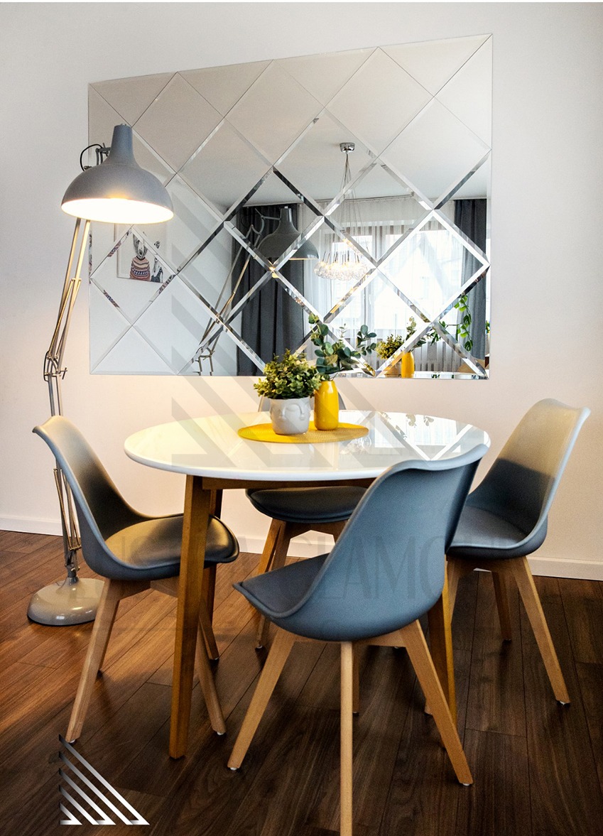 Aranżacja jadalni w Jaworznie z lustrzaną ścianą składającą się z rombów, odbijającą żyrandol i okno, widoczny stół z czterema krzesłami i lampą podłogową.