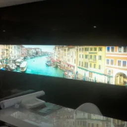 Sufit napinany z podświetlanym motywem weneckim, widoczne zwinięte plany na stole.