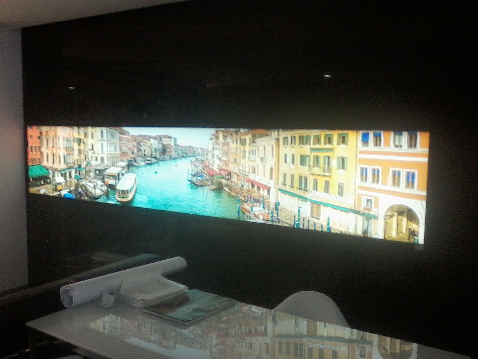 Sufit napinany z podświetlanym motywem weneckim, widoczne zwinięte plany na stole.