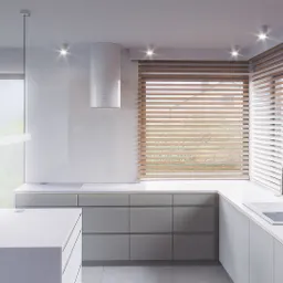 Minimalistyczna kuchnia w jasnych odcieniach szarości i bieli, z drewnianymi żaluzjami w oknie, wyspą z blatem o fakturze lastryko i nowoczesnym oświetleniem.