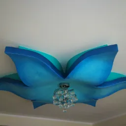 Dekoracyjny sufit w kształcie kwiatu w odcieniach błękitu i turkusu z zamontowanym żyrandolem z kryształkami.