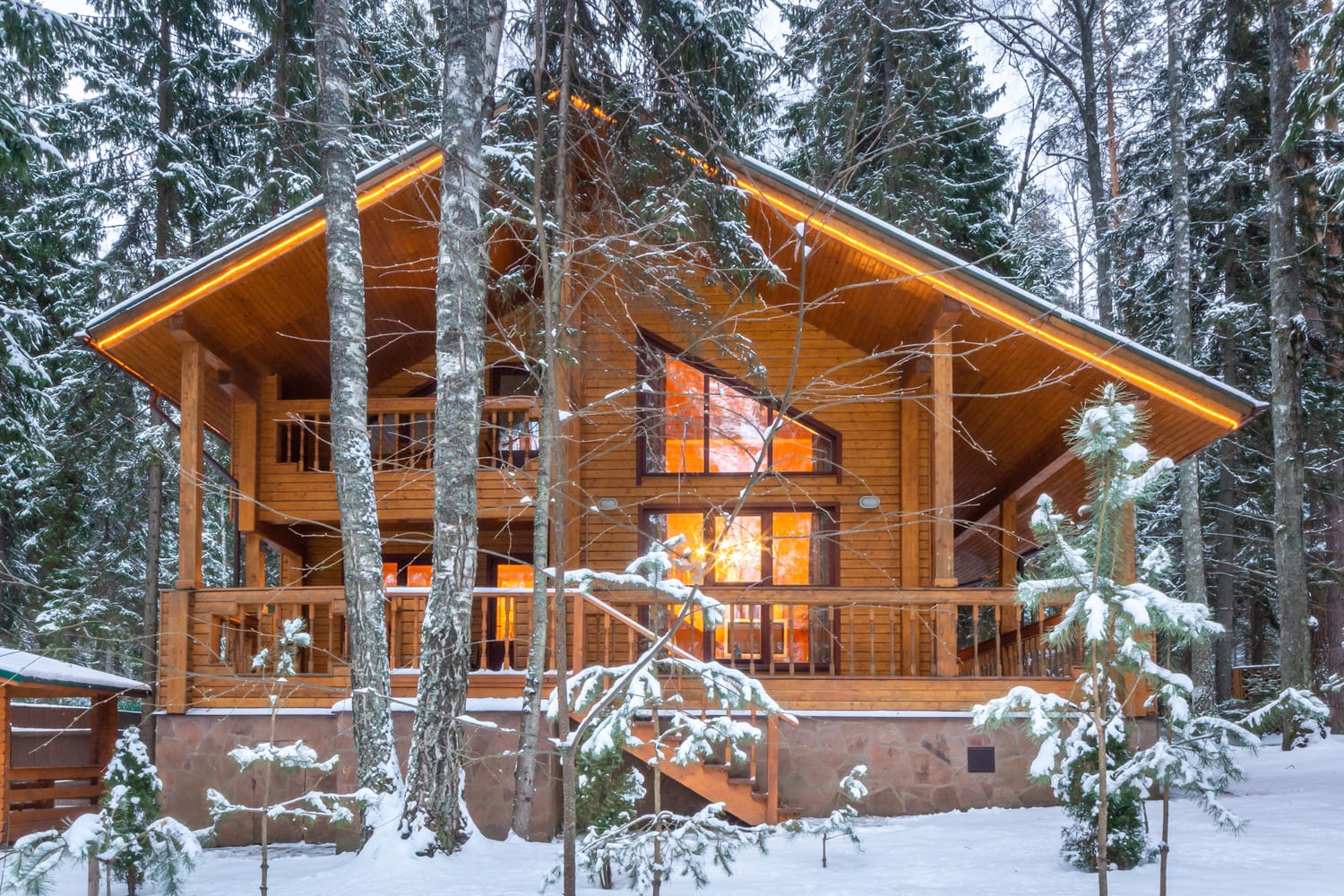 Dwukondygnacyjny drewniany dom z bali z podświetleniem LED na dachu, otoczony zimowym lasem i śniegiem.