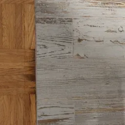 Położenie paneli podłogowych w stylu rustykalnym, imitujących bielone drewno, sąsiadujących z parkietem w jodełkę w Łodzi.