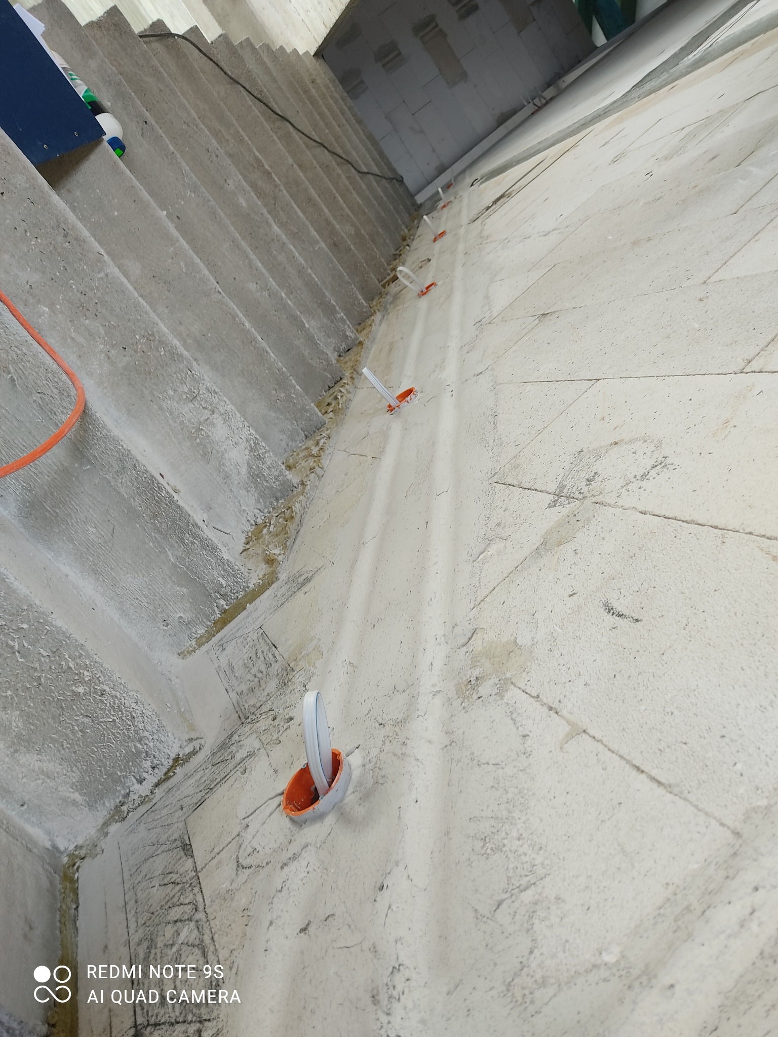 Instalacja elektryczna w surowym wnętrzu: widoczne kable i puszki podtynkowe na ścianie z betonu komórkowego, prowadzone wzdłuż schodów, przygotowane do dalszych prac wykończeniowych.