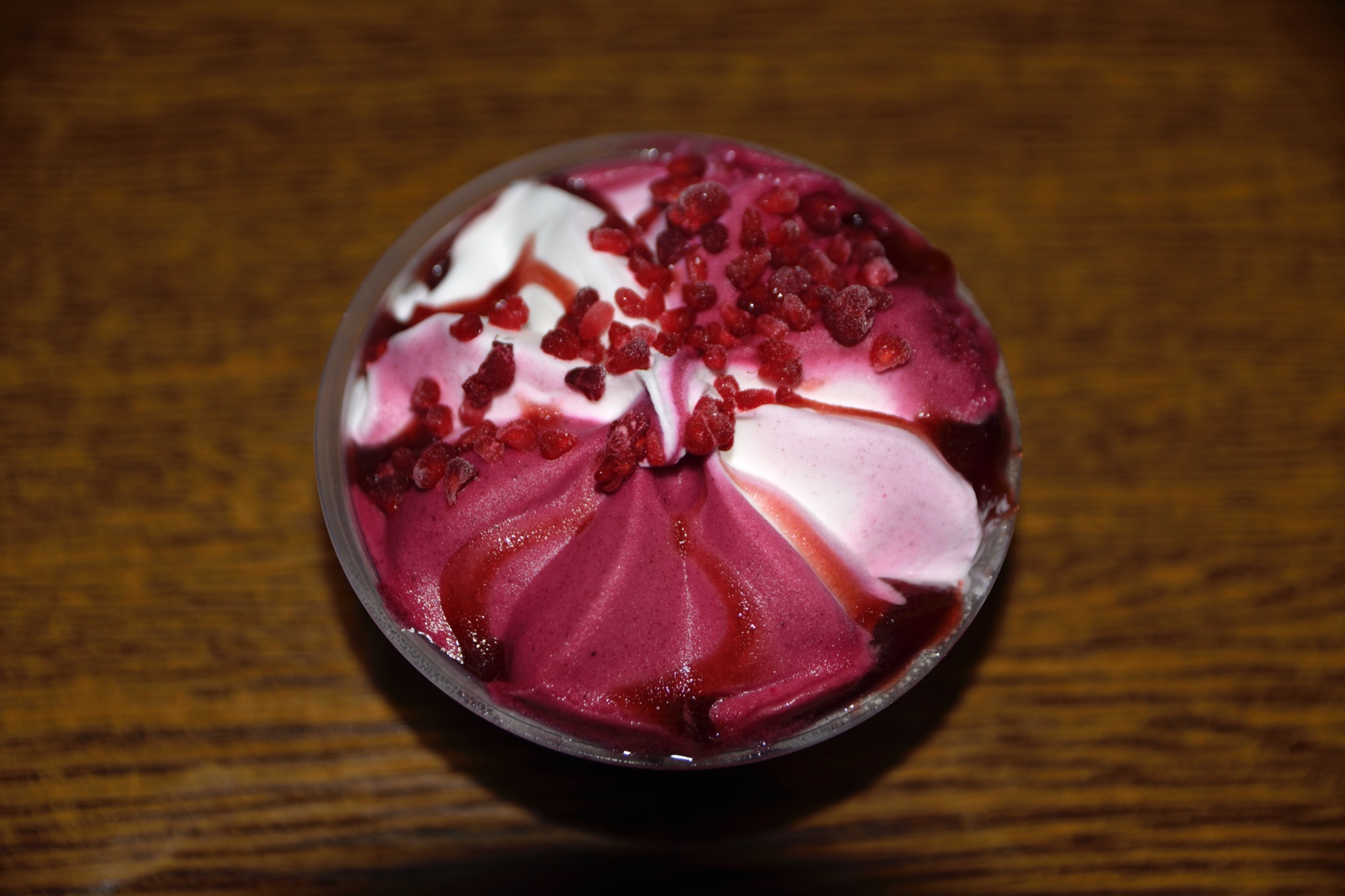 Deser lodowy z owocami leśnymi w przezroczystym kubeczku, widok z góry na drewnianym blacie.