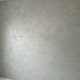 VP Remont Volodymyr Yavorskyi - Ściana pokryta dekoracyjnym tynkiem w odcieniach szarości, z widocznym przewodem elektrycznym i zabezpieczeniem taśmą malarską przy suficie.