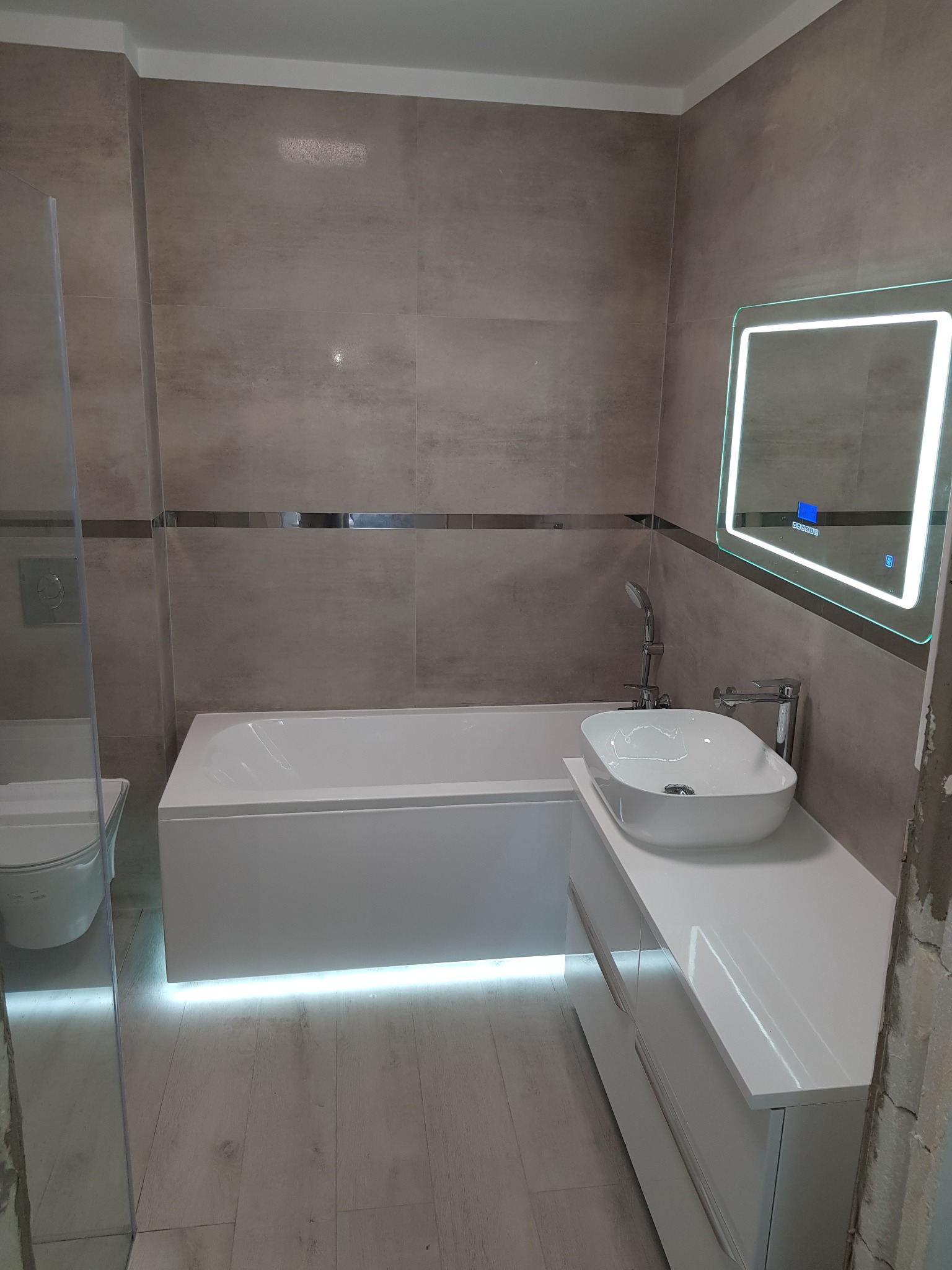 Nowoczesna łazienka z podświetlaną wanną, umywalką nablatową i lustrem z oświetleniem LED.