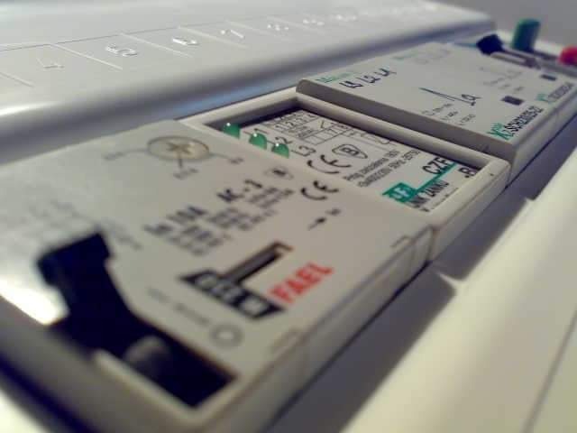 Szczegółowe zbliżenie na wyłączniki różnicowoprądowe w rozdzielnicy elektrycznej, widoczne oznaczenia producenta FAEL i parametry techniczne.
