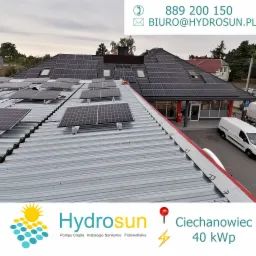 Instalacja paneli słonecznych na dachu budynku w Białymstoku, widok z góry, częściowo zamontowane moduły na metalowej konstrukcji, w tle budynek z zainstalowanymi panelami na dachu skośnym.