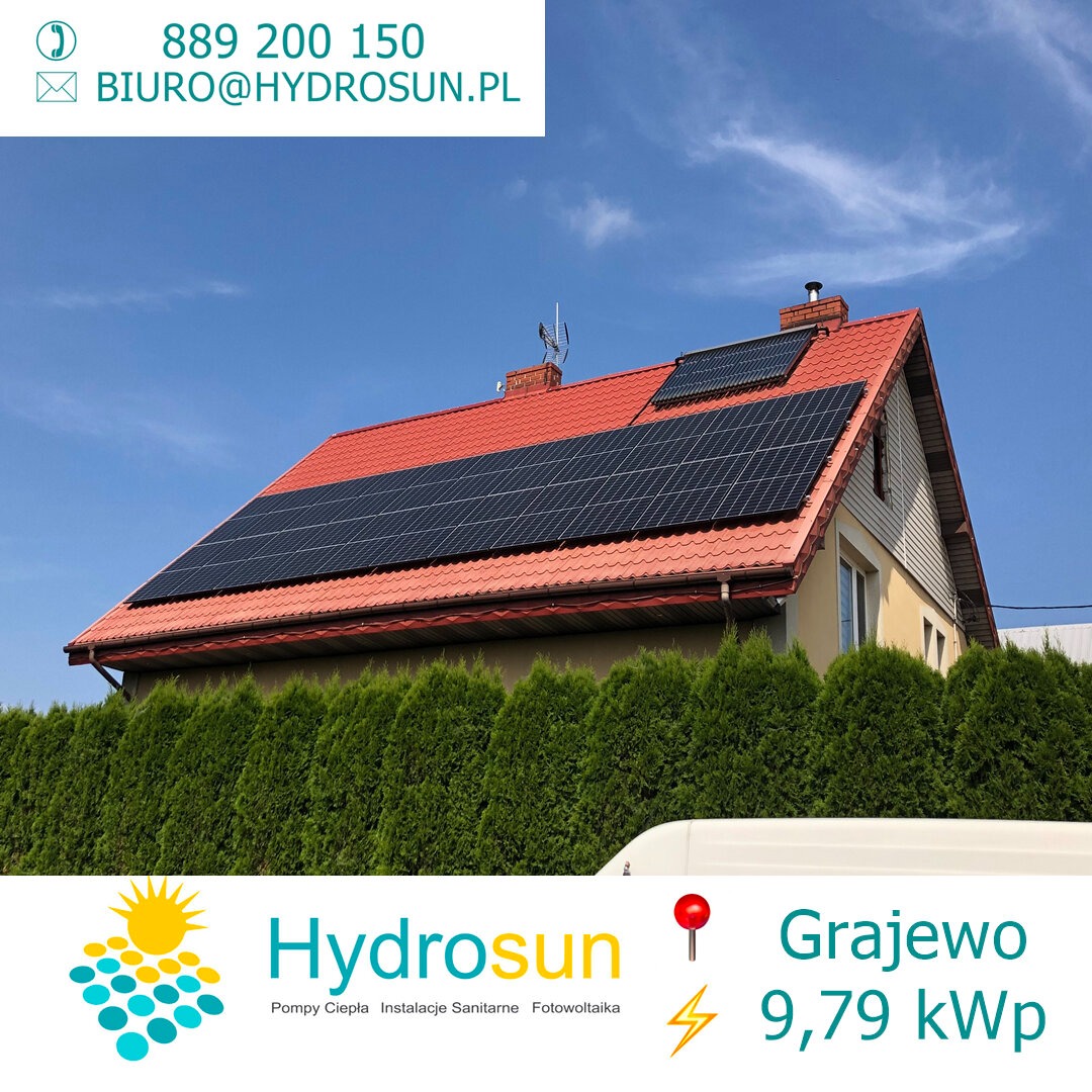 Dom jednorodzinny z czerwonym dachem, na którym zamontowano panele słoneczne, widoczne zza żywopłotu. W tle błękitne niebo z delikatnymi chmurami. W dolnej części zdjęcia widoczne logo firmy...