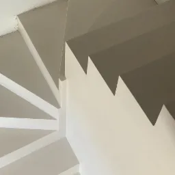 Spiralne schody z jasnoszarą posadzką i białymi ścianami, widok z góry, minimalistyczny design.