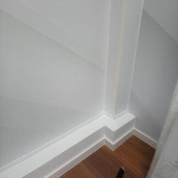 Jan Kohnke - Fragment pomieszczenia z listwami przypodłogowymi, narożnikiem i nożykiem na podłodze z paneli.