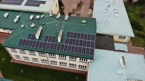 Widok z góry na budynek szkoły w Terespolu z panelami fotowoltaicznymi SUNPOWER P19-405-COM zamontowanymi na zielonym dachu. Widoczny inwerter SOFARSOLAR 30KTL-G2 oraz konstrukcja Van der Valk.