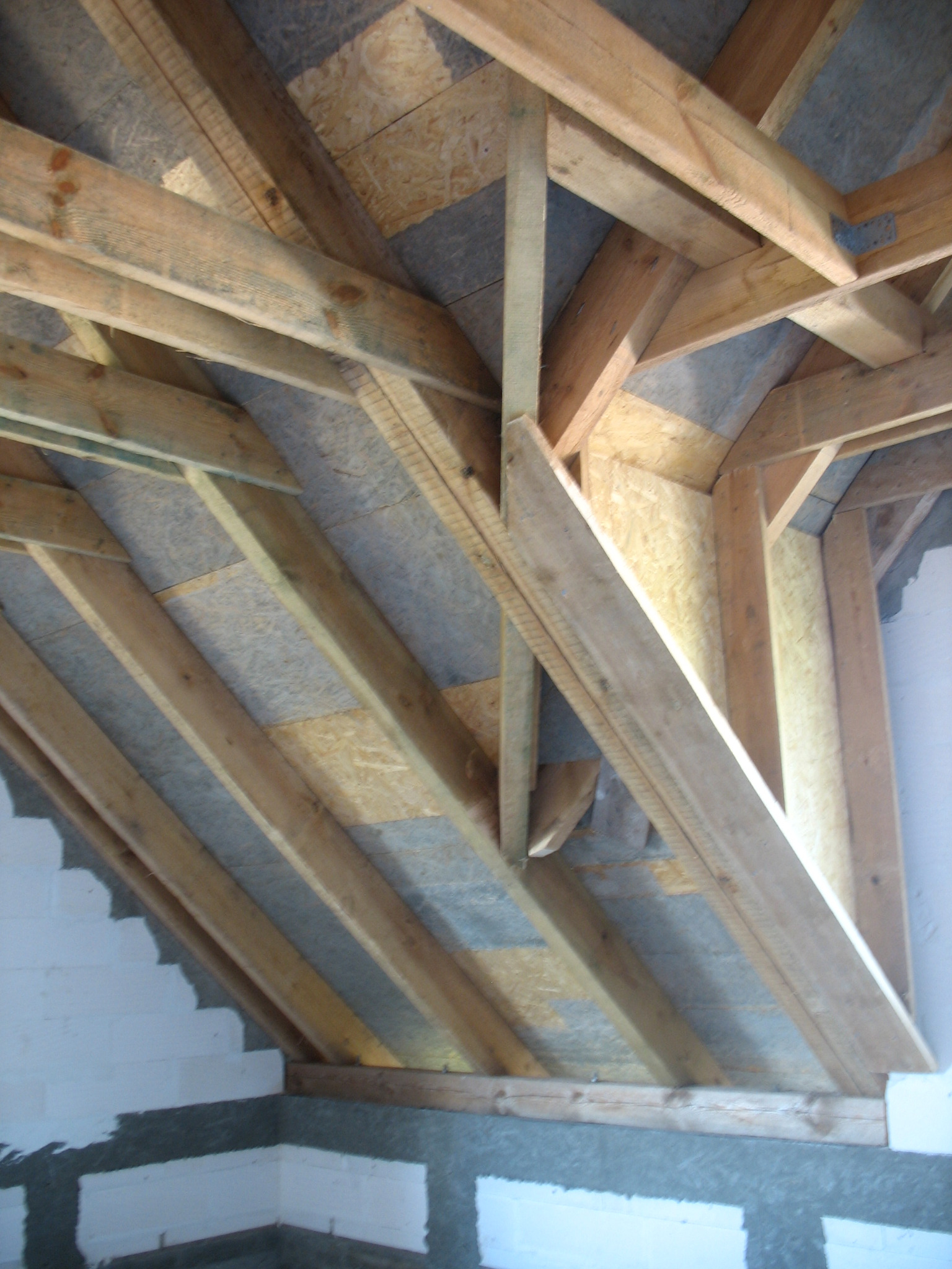 Drewniana konstrukcja dachu w trakcie budowy w Białymstoku, widoczne krokwie, murłata i płyty OSB.