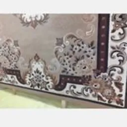 Wzór dywanu z bogatym, brązowo-beżowym ornamentem floralnym i geometrycznym widziany z boku, ukazujący detale tkania i fakturę.