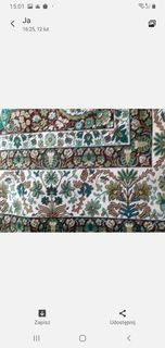 Fragment wzorzystej, wielobarwnej tkaniny z motywami roślinnymi w odcieniach zieleni, brązu i bieli, ułożonej warstwowo.