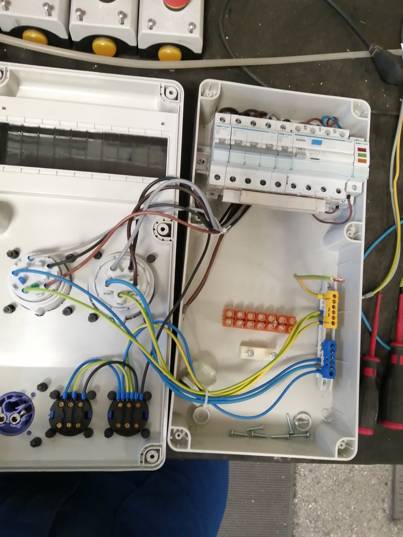 Otwarta skrzynka rozdzielcza z przewodami i bezpiecznikami, widoczne narzędzia, instalacja w trakcie wykonywania w Gnieźnie.