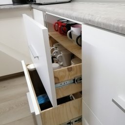 Ciekawe rozwiązanie kuchennych szuflad umożliwiające wykorzystanie dwóch poziomów przy zachowaniu jednego frontu szuflady. Wnętrze zabudowy na życzenie klienta wykonane ze sklejki drewnianej.