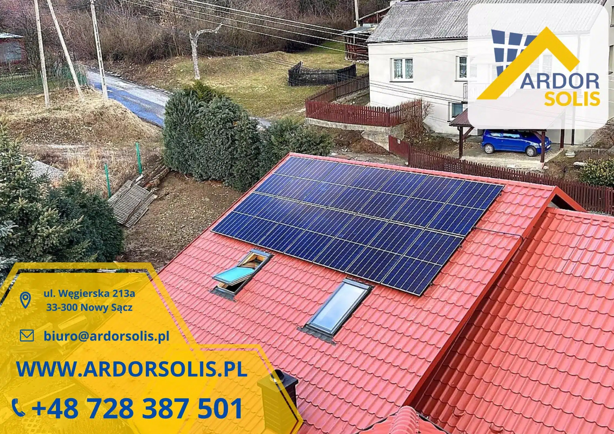 Panel fotowoltaiczny na czerwonym dachu domu jednorodzinnego z dwoma oknami dachowymi, widok z góry, w tle dom, ogród i droga.