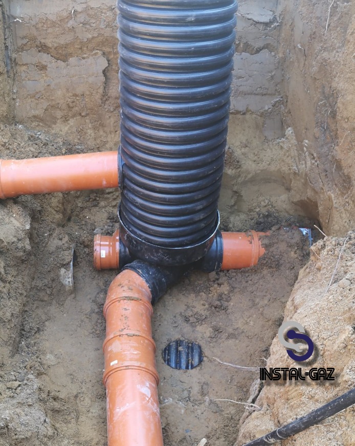 Wykonanie przyłącza gazowego z widocznymi rurami pomarańczowymi i czarnymi, w wykopie ziemnym, z logo firmy w prawym dolnym rogu.