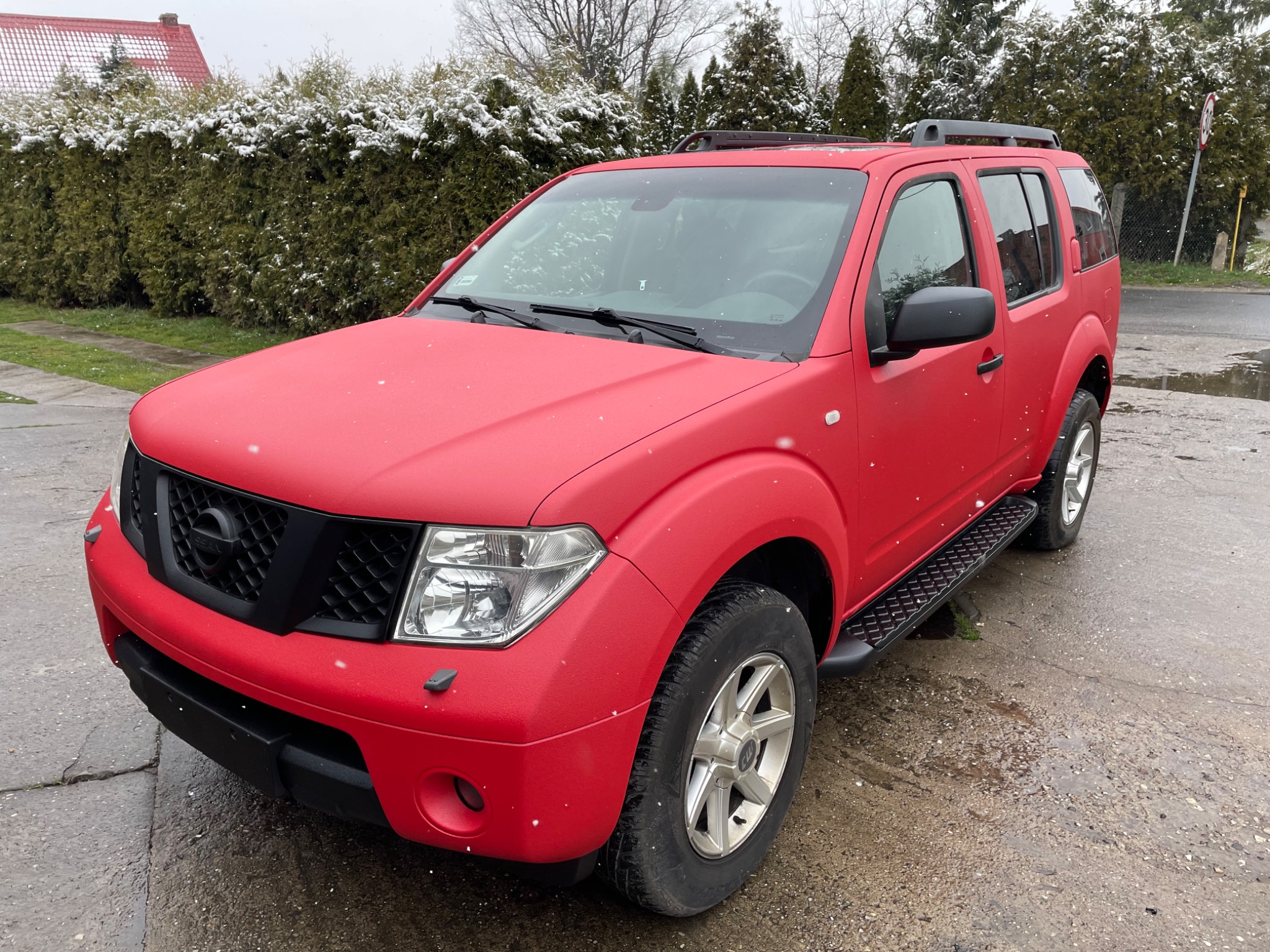 Czerwony Nissan Pathfinder po odświeżeniu lakieru o matowym wykończeniu, stojący na zewnątrz w zimowy dzień, z widocznymi płatkami śniegu.