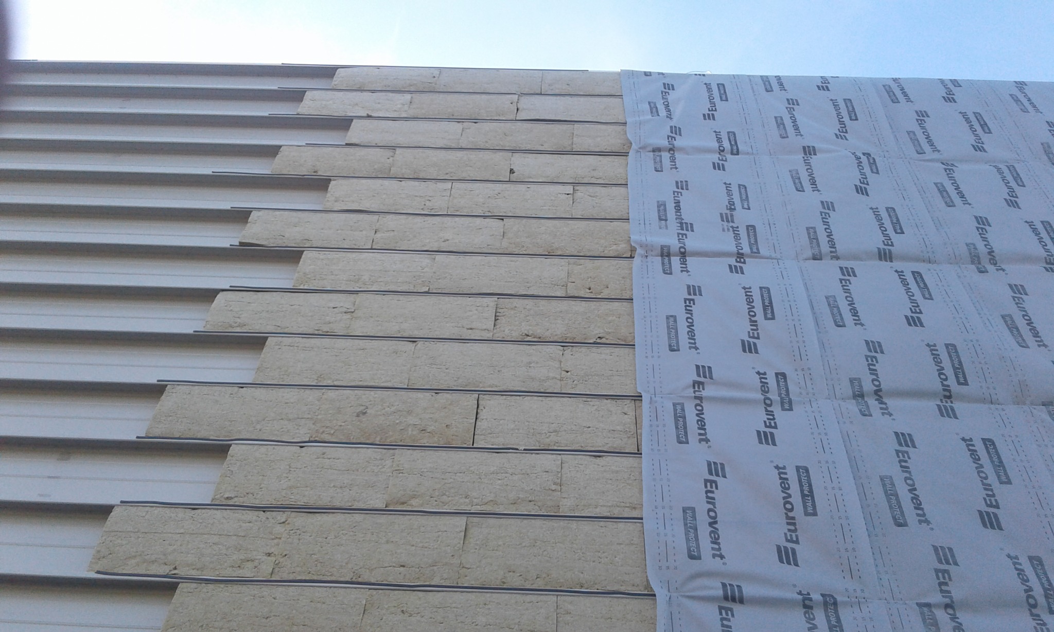 Montaż izolacji termicznej z wełny mineralnej i membrany Eurovent na dachu, widoczne metalowe profile konstrukcyjne.