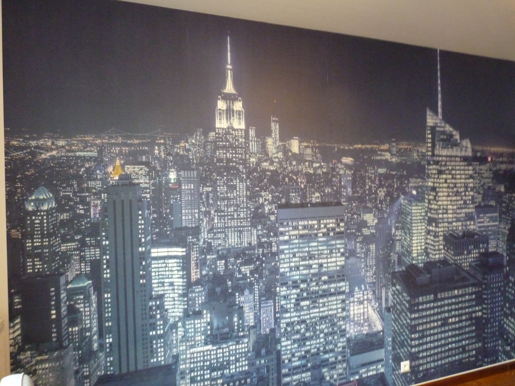 Fototapeta z nocnym widokiem na panoramę Manhattanu, z widocznymi drapaczami chmur i światłami miasta.