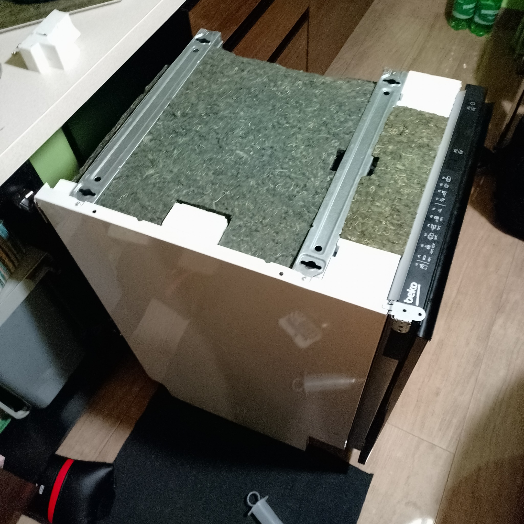 Zdemontowana zmywarka Beko z widocznymi szynami i panelem sterowania, przygotowana do naprawy lub wymiany. Widoczne elementy wnętrza i obudowy.