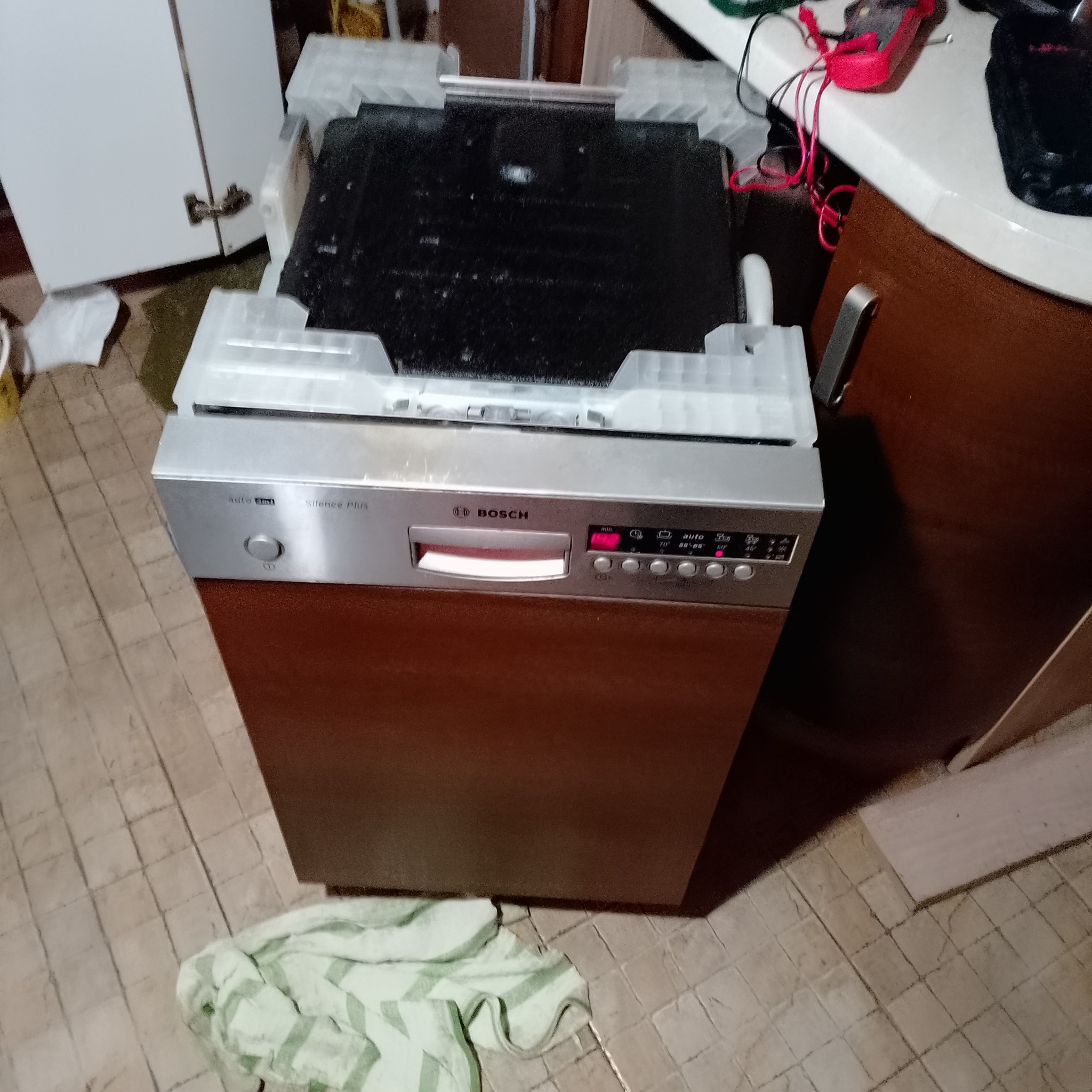 Otwarta zmywarka Bosch Silence Plus w trakcie naprawy, widoczne wnętrze i panel sterowania. Na blacie leżą narzędzia serwisowe.