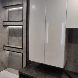 Szara łazienka z podświetlanymi wnękami wyłożonymi płytkami imitującymi beton, białymi szafkami i pralką Beko pod blatem.