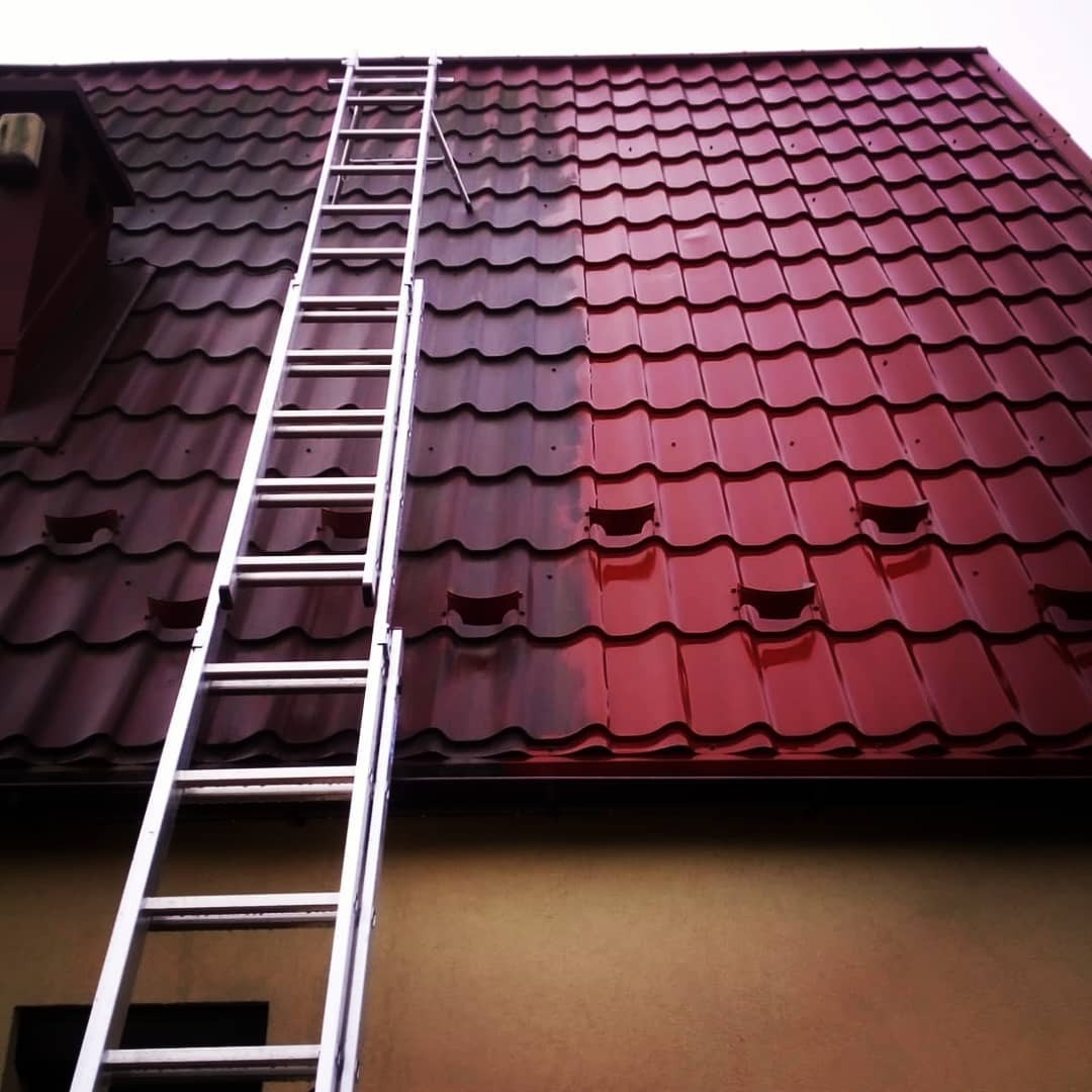 Częściowo umyty, czerwony dach z blachodachówki, widoczna drabina oparta o ścianę budynku.