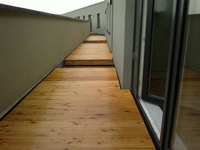 Drewniany taras z desek na zewnątrz budynku, widok z perspektywy, z otwartym oknem.