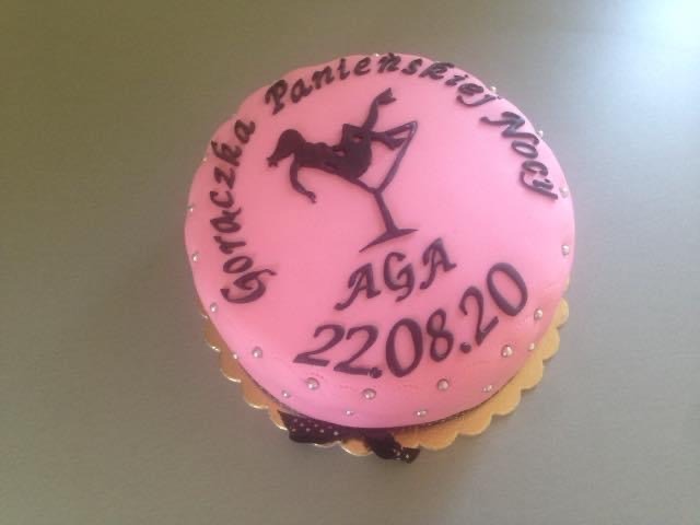 Różowy tort z napisem 'Gorączka Panieńskiej Nocy', sylwetką tancerki w kieliszku, imieniem 'Aga' i datą 22.08.20, ozdobiony srebrnymi kuleczkami i złotą falbanką.