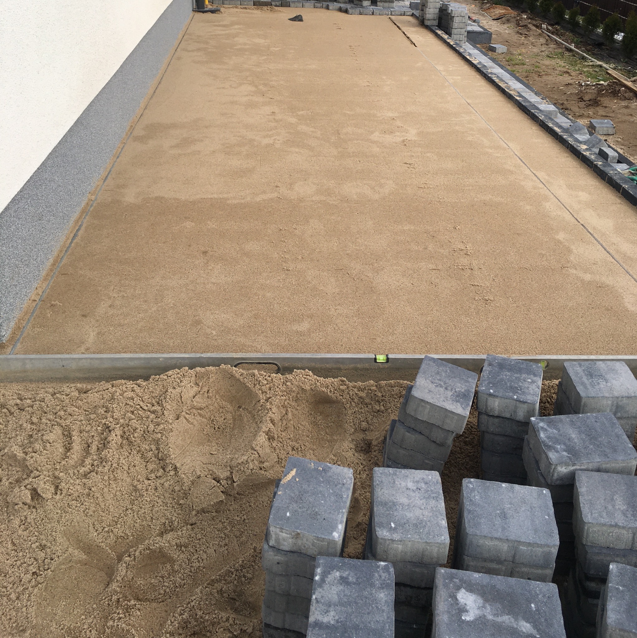 Przygotowanie podłoża pod nawierzchnię z kostki w Sławoborzu: wyrównany piasek, ułożone obrzeża i stos szarych kostek brukowych w rogu.