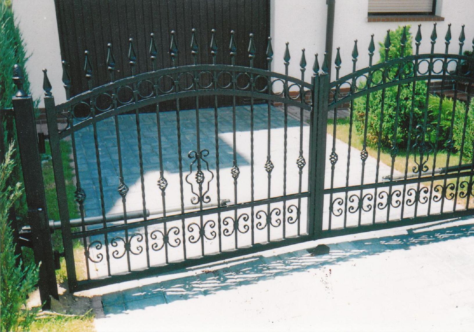Kuta brama wjazdowa z ozdobnymi elementami, wykonana w Skorogoszczy, z widocznymi śladami spawania na dolnej części bramy.