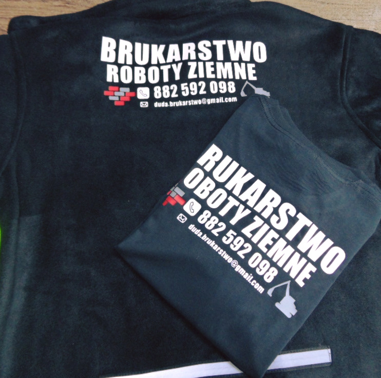 Ciemnozielona bluza polarowa i złożona koszulka z białym nadrukiem: 'BRUKARSTWO ROBOTY ZIEMNE', numerem telefonu i adresem e-mail firmy, obok symbolu koparki i muru z cegieł.