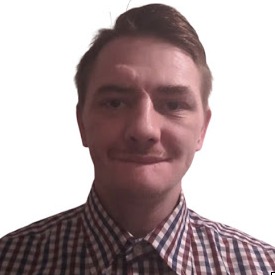 Portret mężczyzny z Katowic w koszuli w kratę, z lekkim uśmiechem i charakterystycznym zaczesaniem włosów.