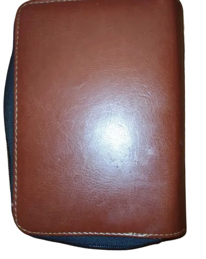 Zamknięty, brązowy, skórzany organizer z czarnym zamkiem błyskawicznym i uchwytem.