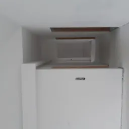 Wnętrze w trakcie prac wykończeniowych: białe ściany, widoczne drewniane elementy konstrukcyjne sufitu, nierówności na ścianach przed finalnym malowaniem.