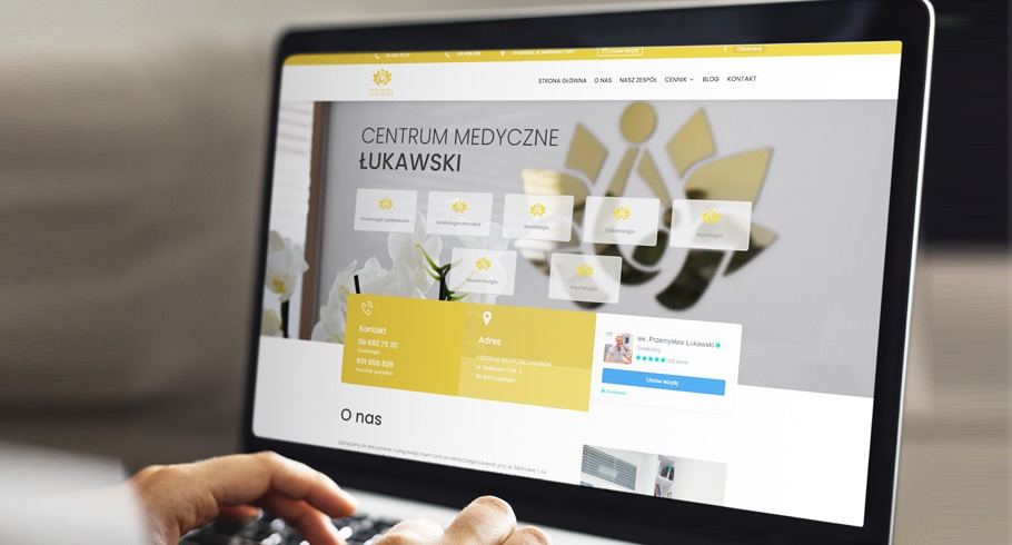 Laptop wyświetlający stronę internetową Centrum Medycznego Łukawski, z widocznymi sekcjami: Strona Główna, O nas, Nasz Zespół, Cennik, Blog, Kontakt oraz panele z ofertą specjalizacji medycznych.