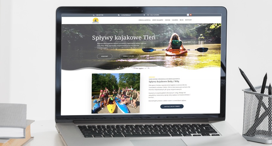 Laptop wyświetla stronę internetową firmy organizującej spływy kajakowe, widoczny nagłówek 'Spływy kajakowe Tleń' oraz zdjęcia z kajaków na tle rzeki i lasu.